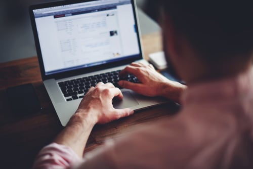 Cropped image of a young man working on his laptop in a coffee shop