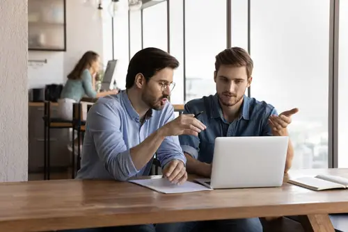 Office employees discussing project at laptop