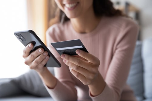 Close up smiling millennial woman holding smartphone and banking credit card