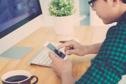 Young man sitting at the table and using smartphone