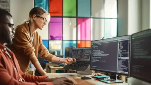 Black Programmer Shows Code On Desktop Computer to Female