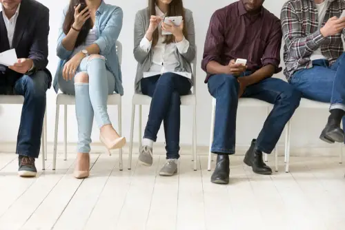 Diverse black and white people sitting in row using smartphones tablets