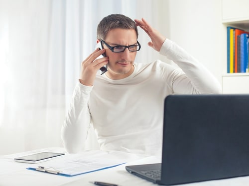 Portrait of young businessman scratching his head while working at home using computer