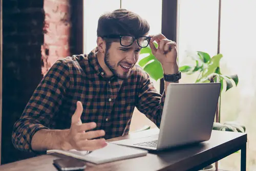 Handsome stressed  young man in glasses using laptop