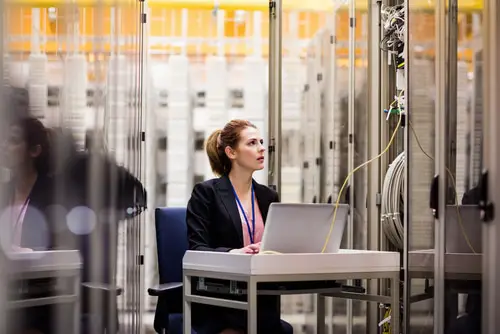 Technician using laptop while analyzing server in server room