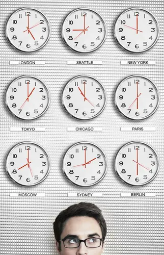 Young businessman in front of clocks showing time across the world