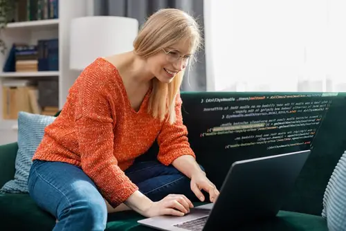Mature smiling woman are coding using laptop from home