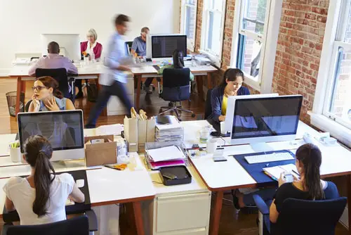 Wide angle view of busy design office with workers at desks